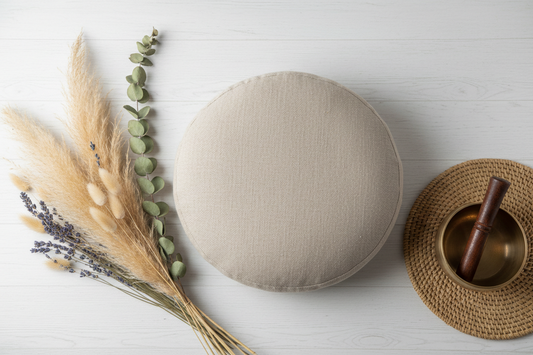 Best meditation cushion for beginners home practice — round zafu with natural linen cover and singing bowl on white surface